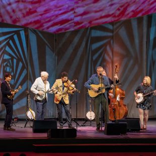 Singer-songwriter Robbie Fulks steps to the microphone with Steven Martin, Alison Brown, and more.