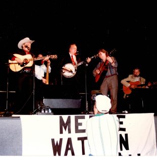 (L to R:) Jim Shumate (fiddle), Mac Wiseman, unknown bassist, Earl Scruggs, Jack Lawrence, and Doc Watson on stage at the Merle Watson Memorial Festival – what would become MerleFest.